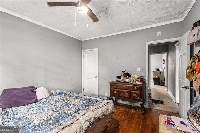 bedroom with ceiling fan, dark hardwood / wood-style flooring, a textured ceiling, and ornamental molding