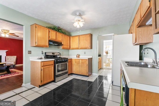 kitchen featuring ceiling fan, stainless steel gas stove, sink, a textured ceiling, and light tile patterned floors