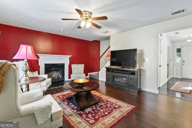 living room with dark hardwood / wood-style flooring, a textured ceiling, and ceiling fan