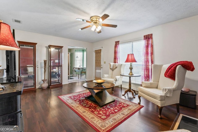 sitting room with ceiling fan, a textured ceiling, and dark wood-type flooring