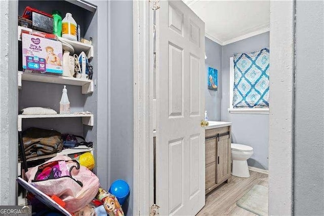 bathroom featuring wood-type flooring, toilet, and crown molding