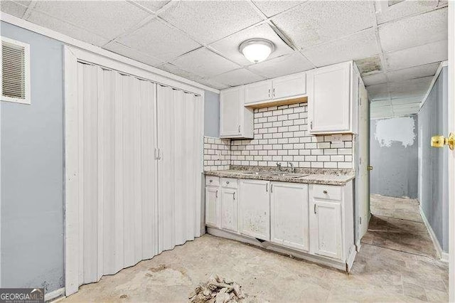 kitchen featuring white cabinets, decorative backsplash, a paneled ceiling, and sink