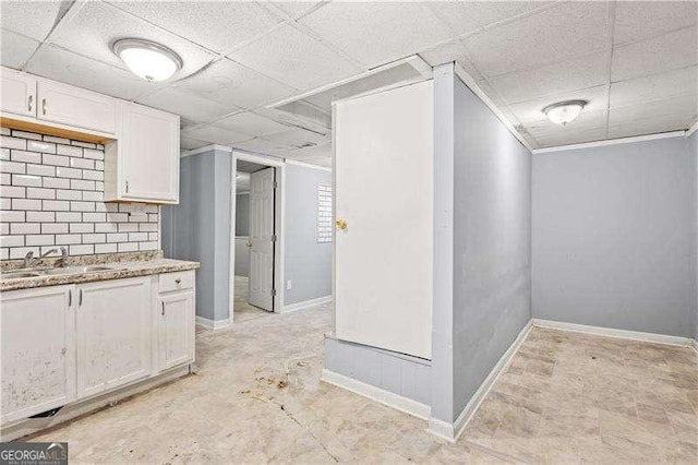 kitchen featuring a paneled ceiling, white cabinetry, and sink