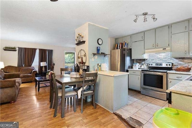 kitchen with appliances with stainless steel finishes, backsplash, light hardwood / wood-style flooring, and gray cabinetry