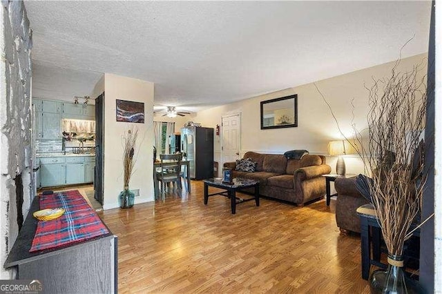 living room featuring a textured ceiling, hardwood / wood-style flooring, and ceiling fan