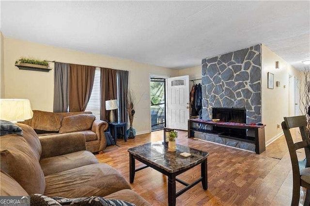 living room featuring a stone fireplace and hardwood / wood-style floors