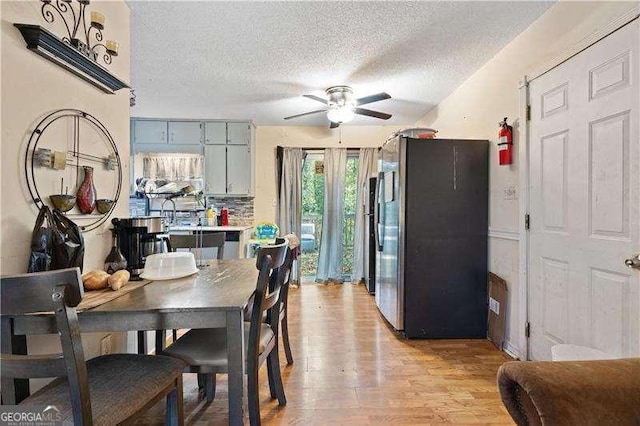 dining area with ceiling fan, a textured ceiling, and light hardwood / wood-style flooring