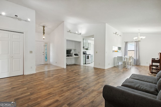 living room with hardwood / wood-style floors, a notable chandelier, track lighting, and vaulted ceiling