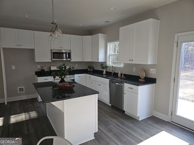 kitchen featuring appliances with stainless steel finishes, dark hardwood / wood-style flooring, sink, white cabinets, and a kitchen island