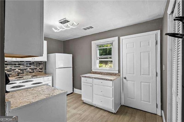 kitchen featuring decorative backsplash, light wood-type flooring, white fridge, and white cabinetry