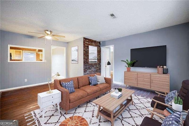 living room with ceiling fan, wood-type flooring, and a textured ceiling