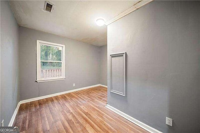 unfurnished room with light wood-type flooring and crown molding