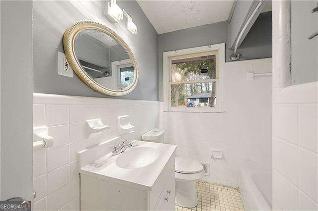 bathroom featuring a bathtub, vanity, tile walls, and toilet