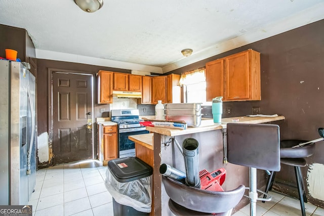 kitchen featuring a kitchen bar, kitchen peninsula, light tile patterned floors, and stainless steel appliances