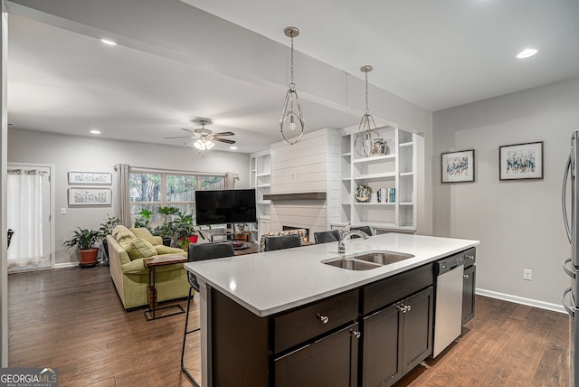 kitchen featuring dishwasher, dark wood-type flooring, sink, hanging light fixtures, and dark brown cabinetry