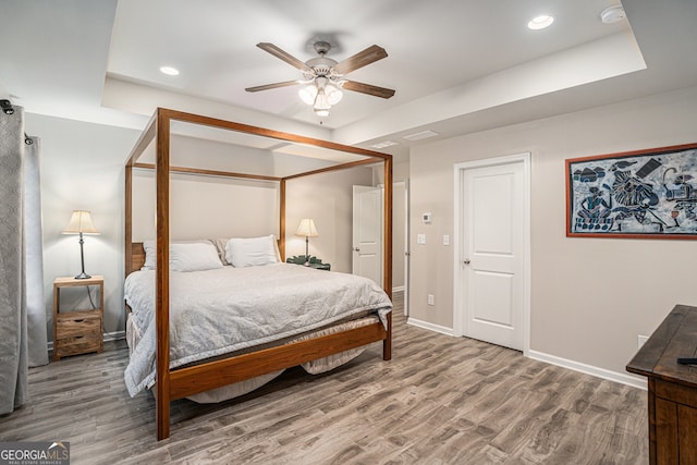 bedroom with a tray ceiling, ceiling fan, and hardwood / wood-style flooring