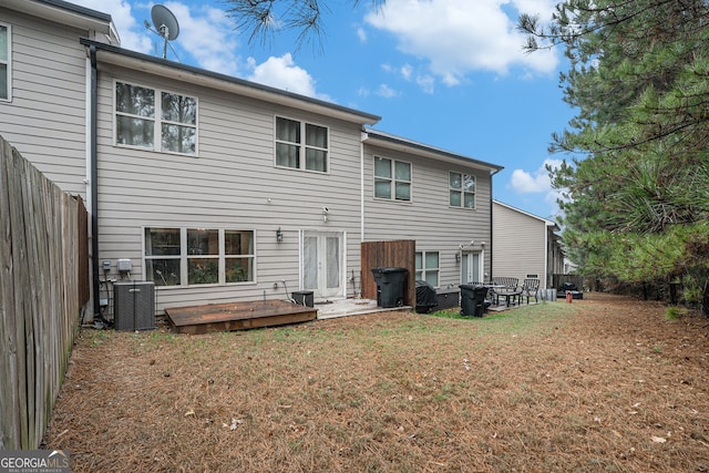 rear view of house with central air condition unit, a wooden deck, and a yard