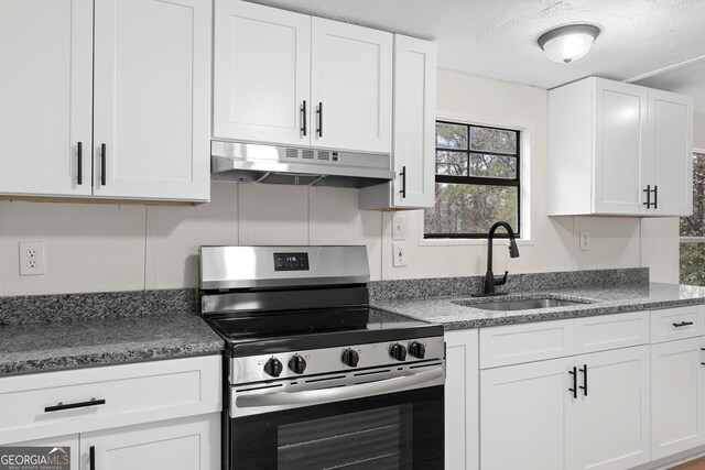 kitchen featuring white cabinets, sink, stainless steel range, and a textured ceiling