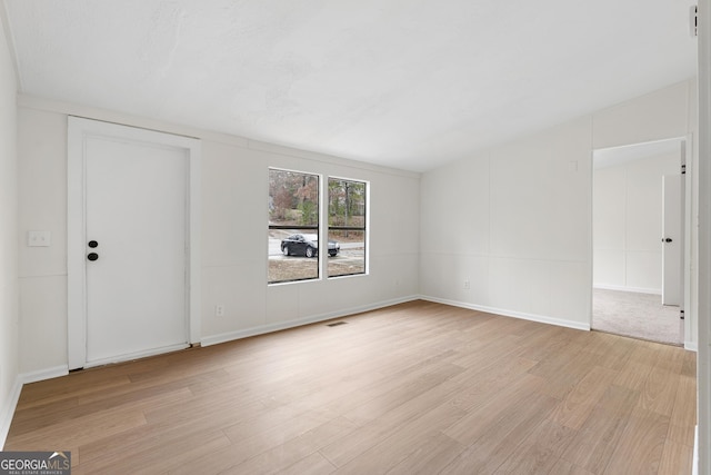 spare room with vaulted ceiling and light hardwood / wood-style flooring