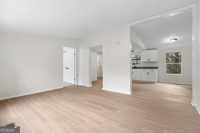 unfurnished living room with vaulted ceiling and light wood-type flooring