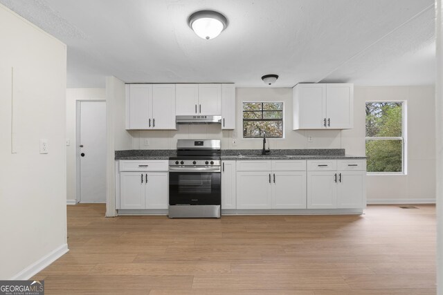 kitchen with white cabinetry, sink, stainless steel range, and light hardwood / wood-style flooring