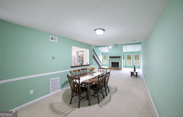 carpeted dining room with a textured ceiling and ceiling fan