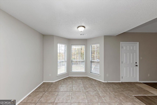 spare room with light tile patterned floors and a textured ceiling