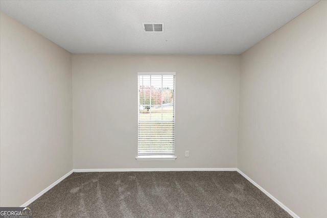 carpeted empty room featuring a textured ceiling