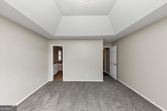 unfurnished bedroom featuring a textured ceiling, carpet floors, and a raised ceiling