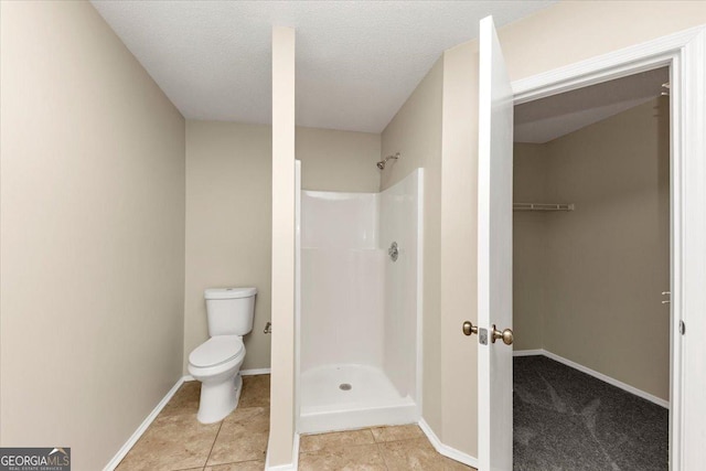 bathroom featuring a shower, tile patterned flooring, a textured ceiling, and toilet