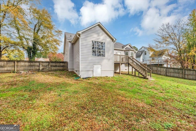 back of house with a deck and a lawn