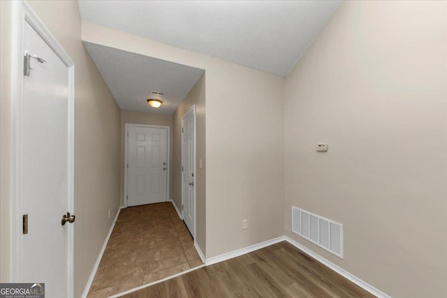 hallway with hardwood / wood-style floors and a textured ceiling