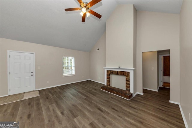 unfurnished living room with ceiling fan, dark wood-type flooring, high vaulted ceiling, and a brick fireplace