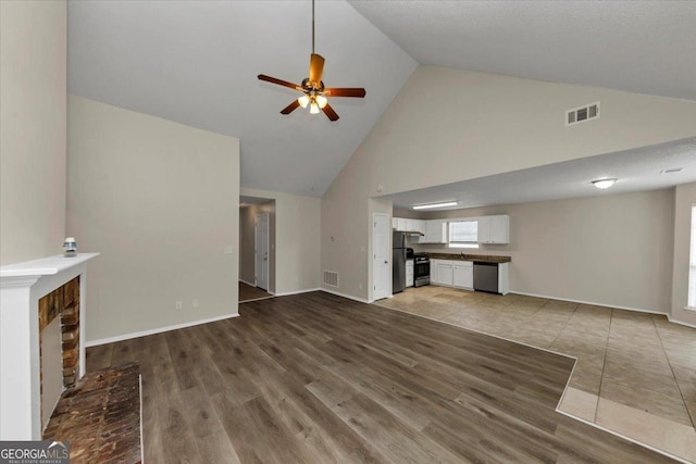 unfurnished living room with ceiling fan, a fireplace, high vaulted ceiling, and hardwood / wood-style flooring