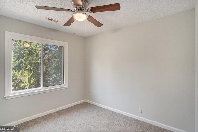 carpeted empty room with ceiling fan, a healthy amount of sunlight, and a textured ceiling