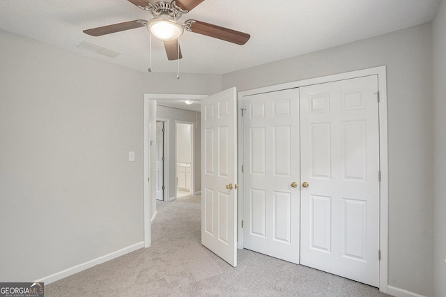 unfurnished bedroom featuring ceiling fan, a closet, light colored carpet, and a textured ceiling