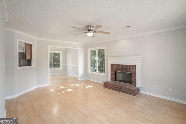 unfurnished living room featuring light hardwood / wood-style floors, a textured ceiling, a wealth of natural light, and a brick fireplace