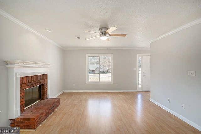 unfurnished living room with light wood-type flooring, a brick fireplace, a textured ceiling, ceiling fan, and crown molding