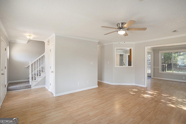 empty room with a textured ceiling, light hardwood / wood-style flooring, and crown molding