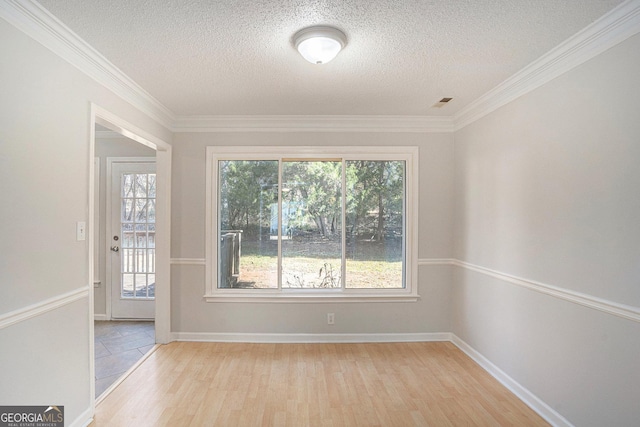 empty room featuring crown molding, light hardwood / wood-style floors, and a textured ceiling