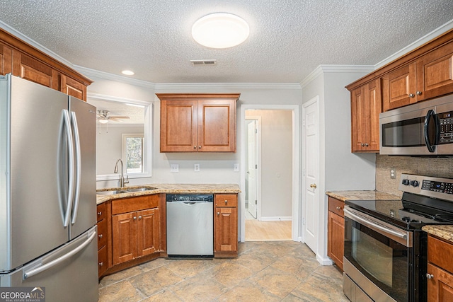 kitchen featuring a textured ceiling, stainless steel appliances, ceiling fan, crown molding, and sink