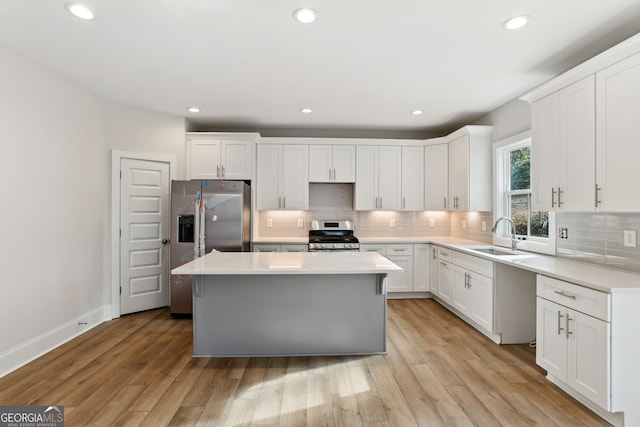 kitchen with white cabinets, stainless steel appliances, light hardwood / wood-style floors, and sink