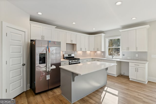 kitchen featuring a kitchen island, white cabinets, stainless steel appliances, and light hardwood / wood-style floors