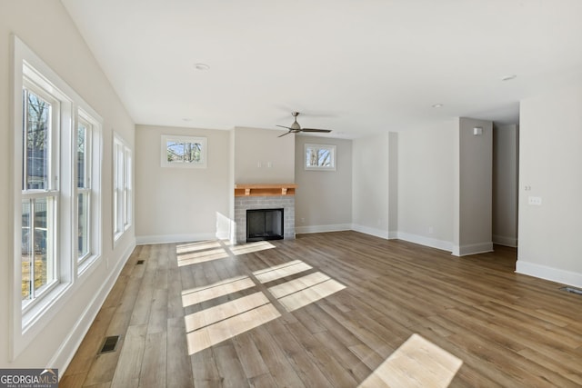 unfurnished living room featuring a fireplace, a wealth of natural light, light hardwood / wood-style flooring, and ceiling fan