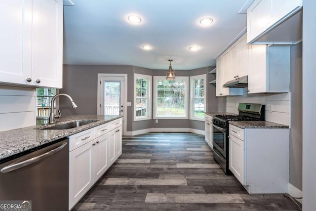 kitchen featuring dark hardwood / wood-style floors, dark stone countertops, pendant lighting, white cabinets, and appliances with stainless steel finishes