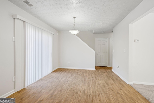 spare room featuring a textured ceiling and light wood-type flooring