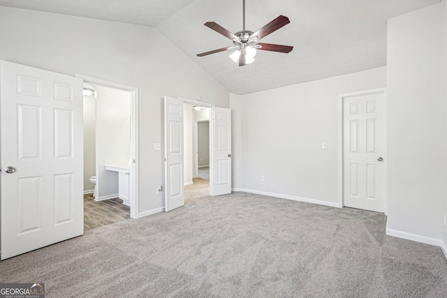 unfurnished bedroom with connected bathroom, carpet floors, high vaulted ceiling, and ceiling fan