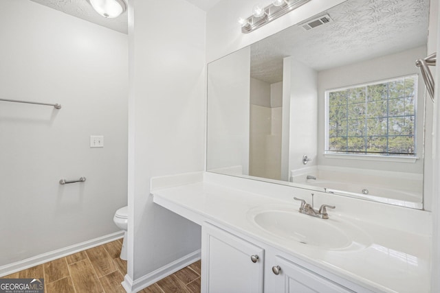 bathroom featuring wood-type flooring, a textured ceiling, toilet, and a bathtub