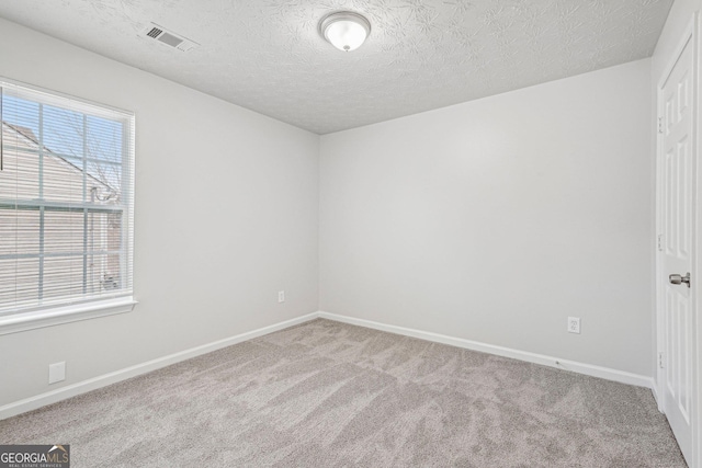 spare room with a textured ceiling and light colored carpet