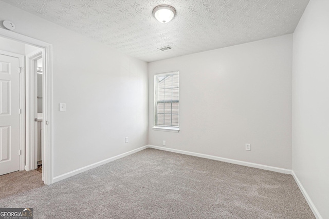 carpeted empty room featuring a textured ceiling